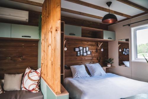- une chambre avec un lit et un mur en bois dans l'établissement Le Village de Cottages - Le Pôle du Cheval et de l'Âne, à Lignières