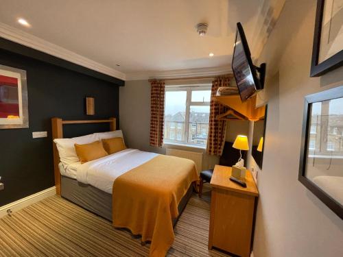 ein Hotelzimmer mit einem Bett und einem TV in der Unterkunft Shandon Hotel in Richmond upon Thames