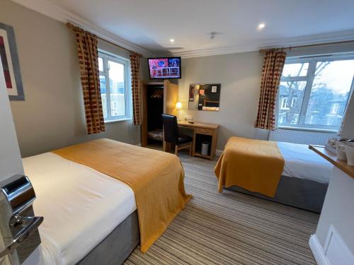 a hotel room with two beds and a desk at Shandon Hotel in Richmond upon Thames