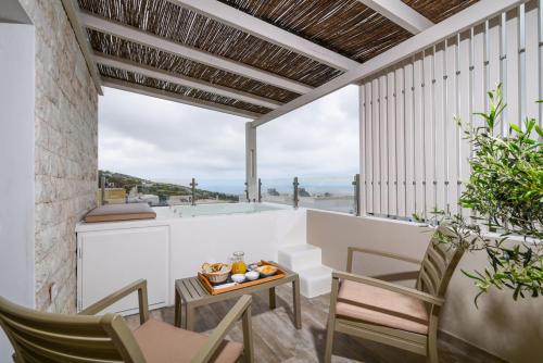 a balcony with chairs and a table and a view of the ocean at Suite Home Santorini in Fira