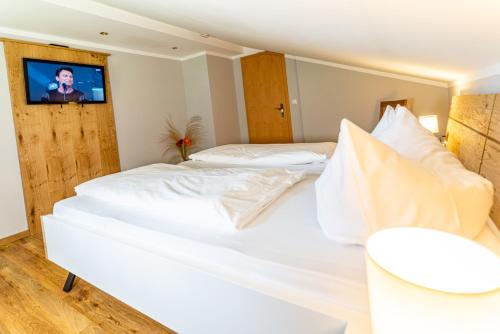 two white beds in a room with a tv on the wall at Gästehaus Hinterponholz in Ramsau