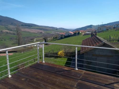 une terrasse en bois avec une balustrade au-dessus d'une maison dans l'établissement Détour en Beaujolais, à Les Ardillats