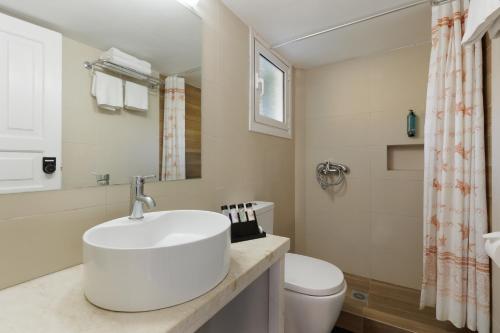 a white bathroom with a sink and a toilet at Century Resort in Acharavi