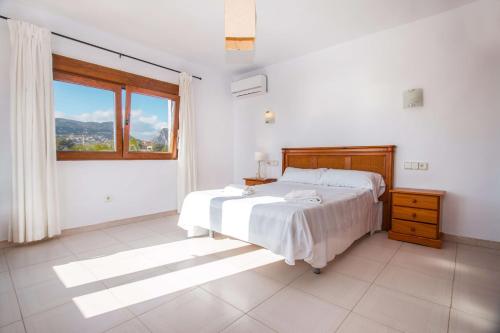 a white bedroom with a bed and a window at Villa Ibiza - PlusHolidays in Calpe