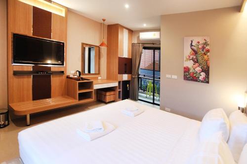 a bedroom with a white bed and a flat screen tv at Avarin Resort in Pak Chong