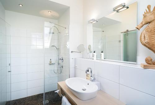 a white bathroom with a sink and a shower at Flussbett Hotel in Gütersloh
