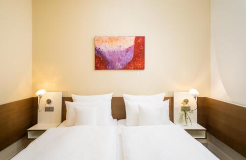 a bedroom with two beds and a painting on the wall at Flussbett Hotel in Gütersloh