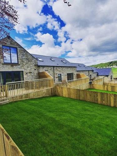 a house with a fence in front of a yard at Beech Cottage in Rothbury