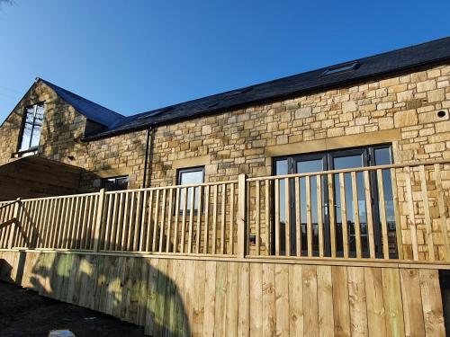 a wooden fence in front of a stone building at Copper Cottage in Rothbury