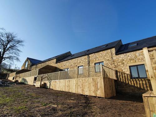a brick building with a fence on the side of it at Copper Cottage in Rothbury