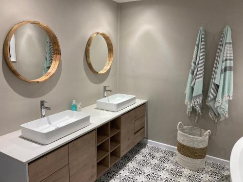 a bathroom with two sinks and mirrors on the wall at Glentana Beach Rental in Groot Brak Rivier