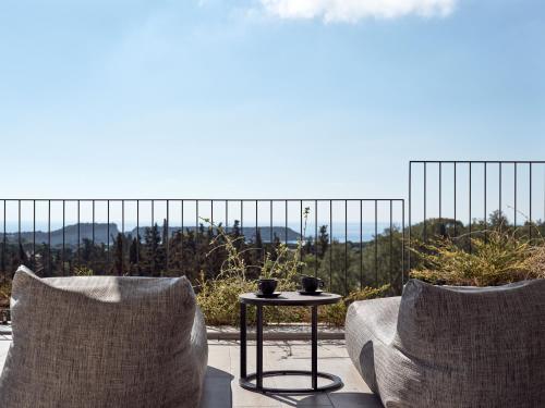 a patio with two chairs and a table with a view at Alexandra SeaView Luxurious Villa, By ThinkVilla in Vasilikos