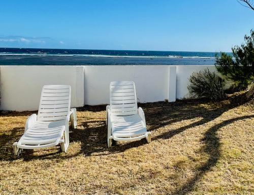 two white chairs sitting on the sand near the ocean at Villa Maimouna les pieds dans l'eau in Saint-Pierre