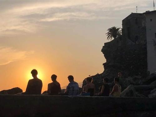 a group of people sitting on a ledge watching the sunset at I Tre Merli Locanda in Camogli