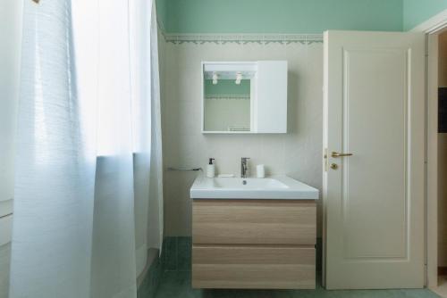 een badkamer met een witte wastafel en een spiegel bij HouSmart San Lazzaro Salvo D'Acquisto 16 in San Lazzaro di Savena