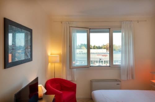 una camera con un letto, una sedia rossa e una finestra di HouSmart San Lazzaro Salvo D'Acquisto 16 a San Lazzaro di Savena