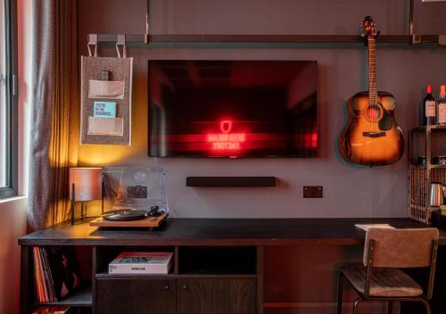 a desk with a tv and a guitar on a wall at BrewDog DogHouse Manchester in Manchester
