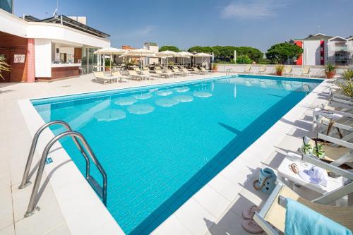 a pool at a hotel with chairs and umbrellas at Hotel Jasminum in Bibione