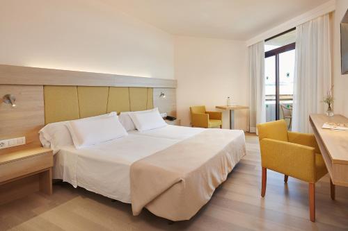 a bedroom with a large white bed and a desk at Hotel Sabina Playa in Cala Millor