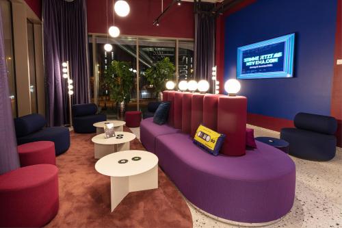 sala de estar con sofá púrpura y mesas en ibis Styles Muenchen Perlach, en Múnich