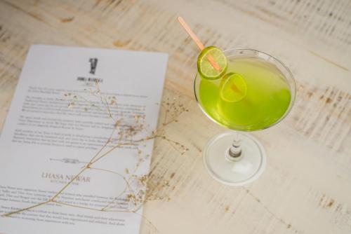a drink sitting on a table next to a book at Tree of Life Indra Mandala Hotel, Gangtok in Gangtok