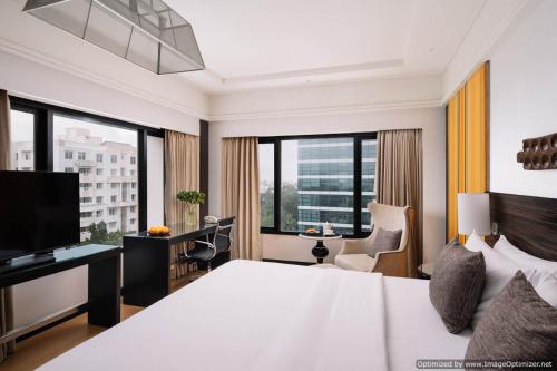 Habitación de hotel con cama, escritorio y ventanas en The Raintree, St. Mary’s Road, en Chennai