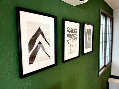 four framed pictures on a green wall with windows at Swiss Inn in Sapporo