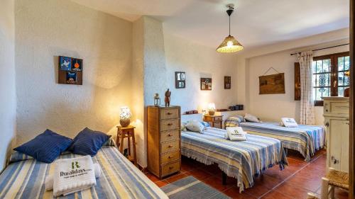 sypialnia z 3 łóżkami i komodą w obiekcie Cortijo La Alberquilla Íllora by Ruralidays w mieście Illora