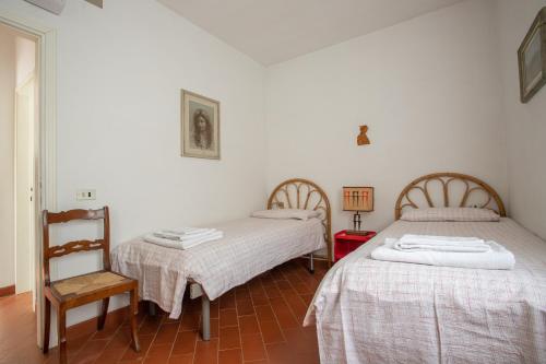 pokój z 2 łóżkami i krzesłem w obiekcie Casa Le Cellane w mieście Castel del Piano