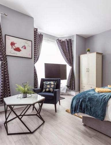a bedroom with a bed and a chair and a table at 4 bedroom house, 2 Min Walk From Station in London