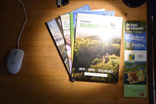 three brochures and a computer mouse on a table at Ferienwohnung Happynest in Birresborn