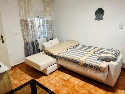 a bed and a chair in a room at Estudio adosado acogedor con jardín, barbacoa y parking privado in Alicante