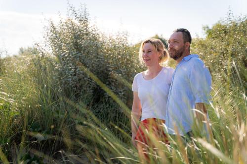a man and woman walking through the tall grass at Strandhafer Aparthotel in Warnemünde