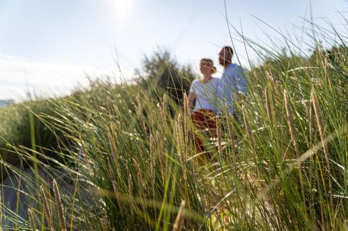 two people sitting on top of some tall grass at Strandhafer Aparthotel in Warnemünde