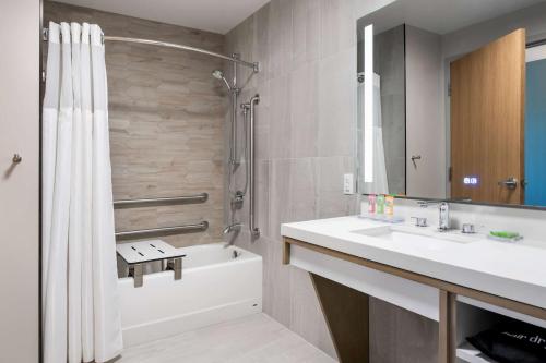a bathroom with a tub and a sink and a shower at Wyndham Garden Winnipeg Airport in Winnipeg