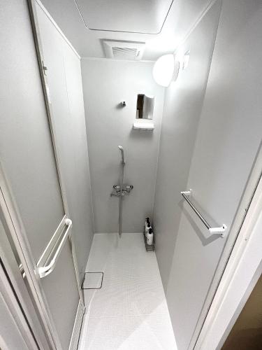 a white bathroom with a shower and a toilet at Swiss Inn in Sapporo