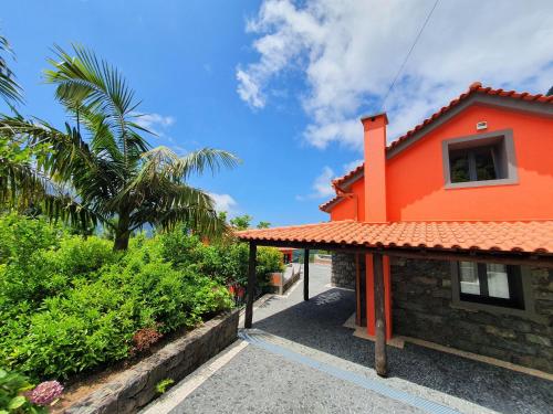 an orange house with a palm tree and bushes at Mountain-Ocean-View Madeira in São Vicente