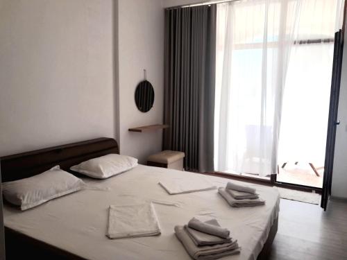 1 dormitorio con 1 cama con sábanas blancas y ventana en Balchik Gardens complex SeaHome 21 apartment, en Balchik