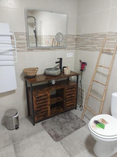ein Badezimmer mit einem hölzernen Waschtisch mit einem Spiegel und einem WC in der Unterkunft Maison de bourg paisible in Parçay-sur-Vienne