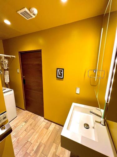a bathroom with a sink and a brown door at Swiss Inn in Sapporo