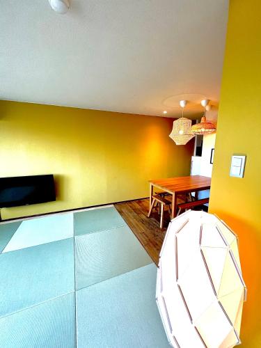 a living room with a table and a yellow wall at Swiss Inn in Sapporo