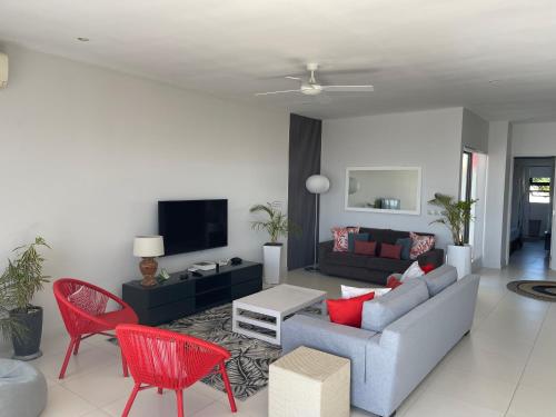 a living room with a couch and red chairs at Cap Ouest Beachfront Luxury Penthouse & Apartment in Flic-en-Flac