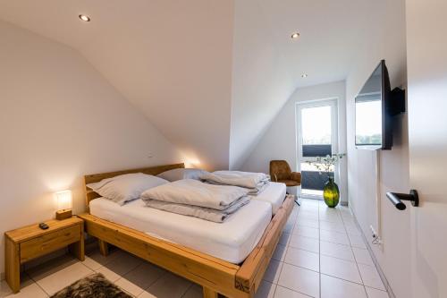 a bedroom with a bed with white sheets and pillows at Ferienpark Harkebrügge Haus Spiekeroog in Barßel