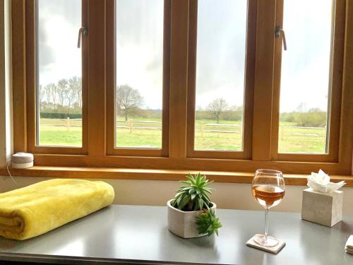 a table with a glass of wine and a window at Quality Oak Barn with Hot Tub and Parking in Bramley