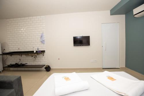 a room with two white beds and a tv on the wall at Jahu Center Plaza Flats in Jaú
