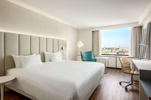 a hotel room with a large white bed and a window at NH Utrecht in Utrecht