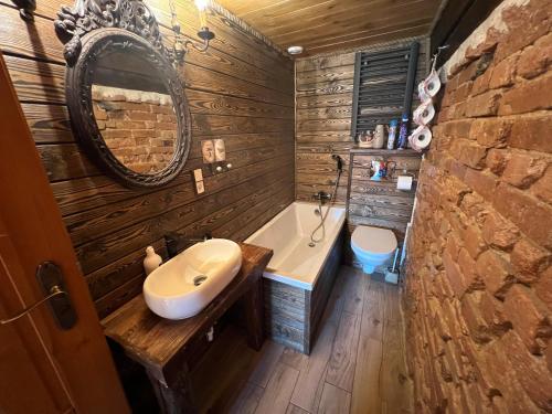 a bathroom with a tub and a sink and a mirror at Zacisze 13 in Leśna