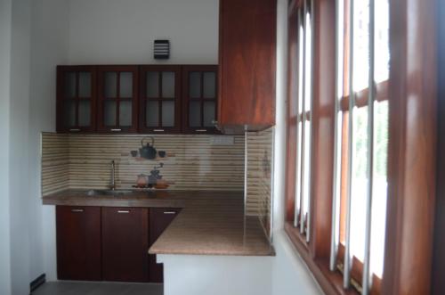 a kitchen with wooden cabinets and a sink and a window at Villa A in Galle