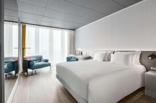 a bedroom with a large white bed and a desk at nhow Rotterdam in Rotterdam