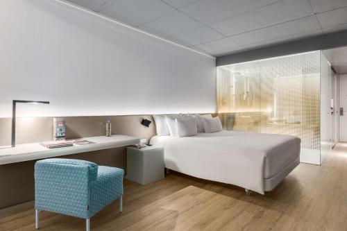 a bedroom with a white bed and a blue chair at nhow Rotterdam in Rotterdam